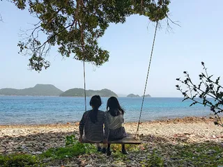 海辺のブランコに座る二人
